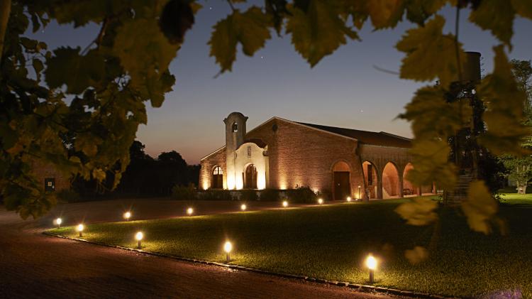 Foto nocturna de la bodega bouza con el casco principal. Caminos de ingreso iluminados. 