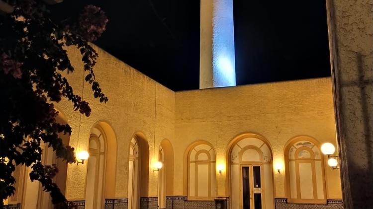 Foto nocturna del patio del edificio del Museo donde se ve el piso en forma de damero, una fuente central y en el fondo las salas del museo y la torre 