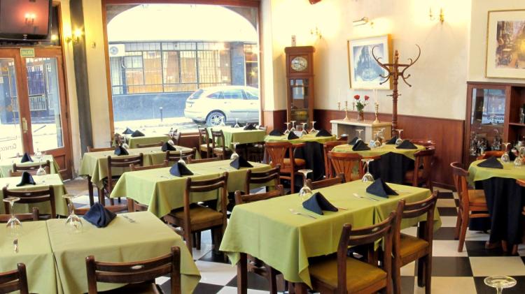 Foto del salón principal con su piso en damero, mesas y sillas con manteles verde lima 