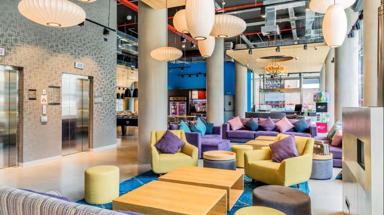 Lobby del hotel. Hay sillones de diversos tamaños y colores. Al fondo hay una mesa de pool, una heladera con bebidas y mesas con sillas.