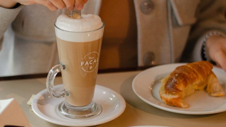 merienda bar facal: persona tomando un capuchino con medialunas y sandwiches
