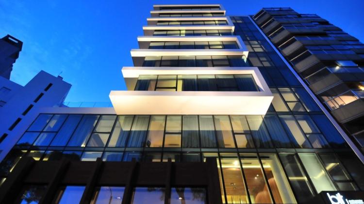 Moderna fachada del Bit Design Hotel. 9 pisos con frente vidriado, separados por rectángulos de cemento blanco incompletos, sin un lateral.