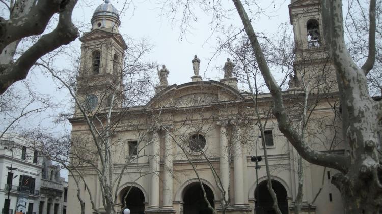 Fachada de la Iglesia Matriz. Al centro un gran portal, con dos columnas a cada lado y un vitral redondo encima. Arriba, en el techo, hay tres estatuas.