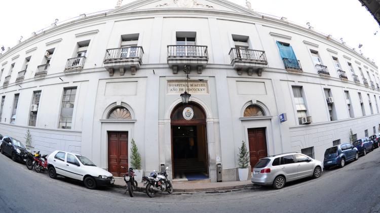 Foto tomada con angulo especial que da la impresión de estar el edificio apaisado. Edificio antiguo en varios pisos de color blanco. 