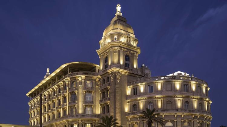 Fachada del hotel Sofitel Casino Carrasco en la tardecita noche. Los detalles arquitectónicos están destacados con luces verticales hacia arriba.